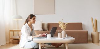Kvinde sidder i sin stue og researcher på sin computer