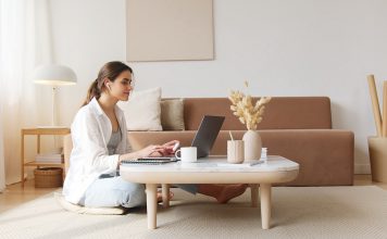 Kvinde sidder i sin stue og researcher på sin computer